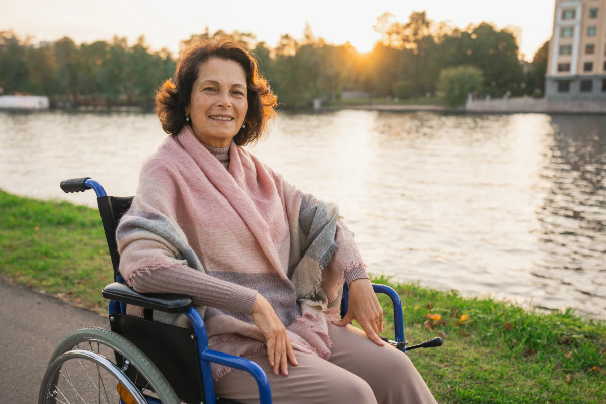 Smiling woman in a wheelchair beside a lake